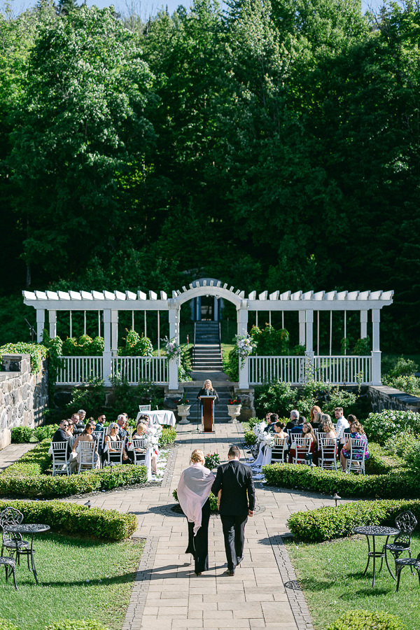 Le marié et sa mère marchent dans l'allée lors de la cérémonie de mariage, dans les jardins italiens du Stonehaven.