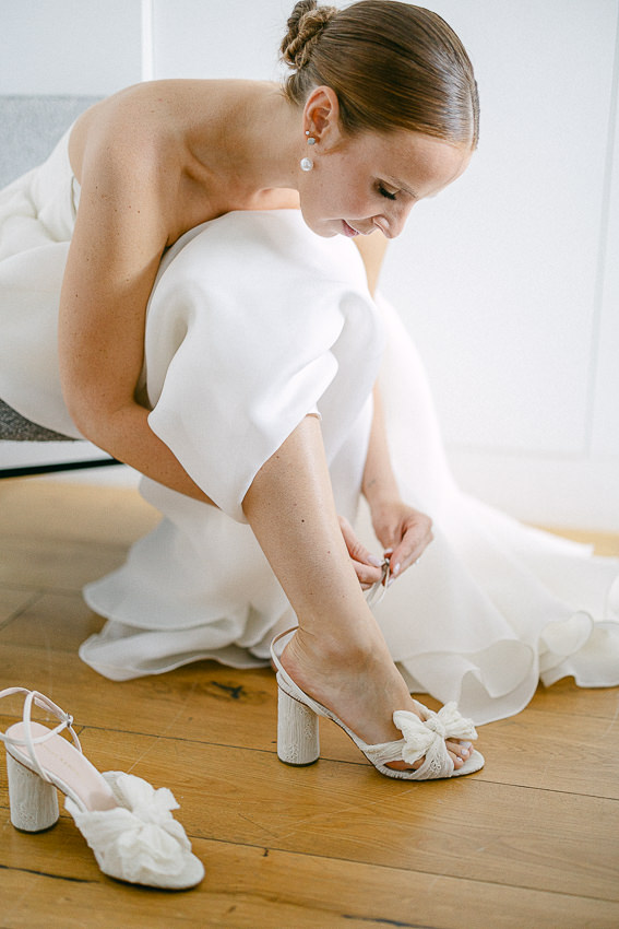 La mariée enfile ses chaussures de mariage.