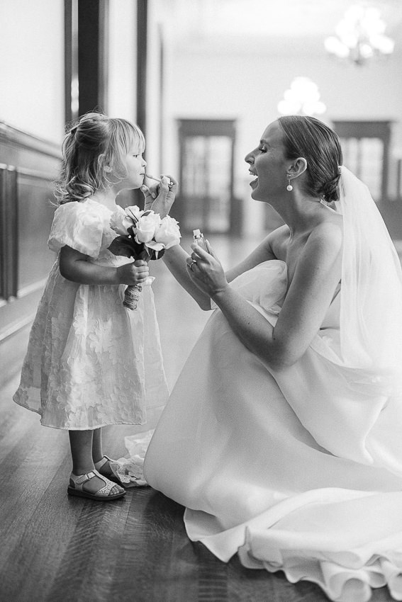 La mariée met du rouge à lèvre à une petite bouquetière.