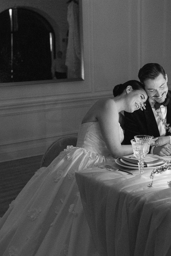 Les mariés sont souriants, assis à la table d'honneur, sous la lueur des chandelles. Wedding planner à Montréal : Agence Auréa