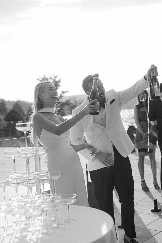 Les mariés ouvrent une bouteille de champagne au moment du cocktail pour célébrer leur mariage avec les invités