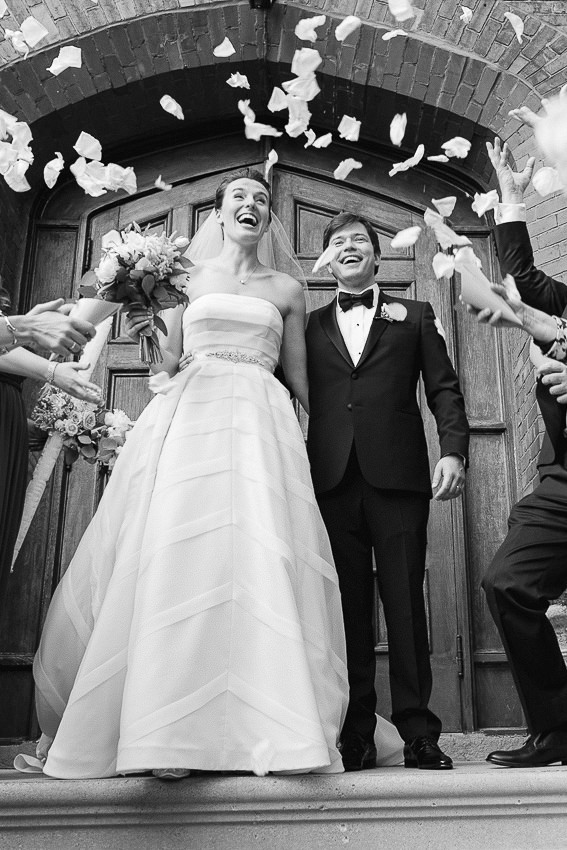 Les mariés sont devant la porte de l'église et les invités lancent des confettis